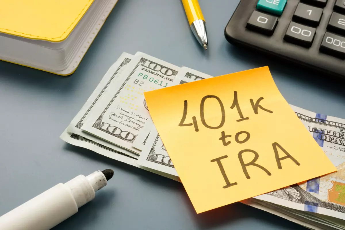 Stack of $100 bills with "4o1(k) to IRA" written on sticky note 