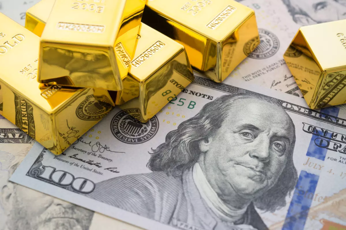 Stacked gold bars and $100 bills