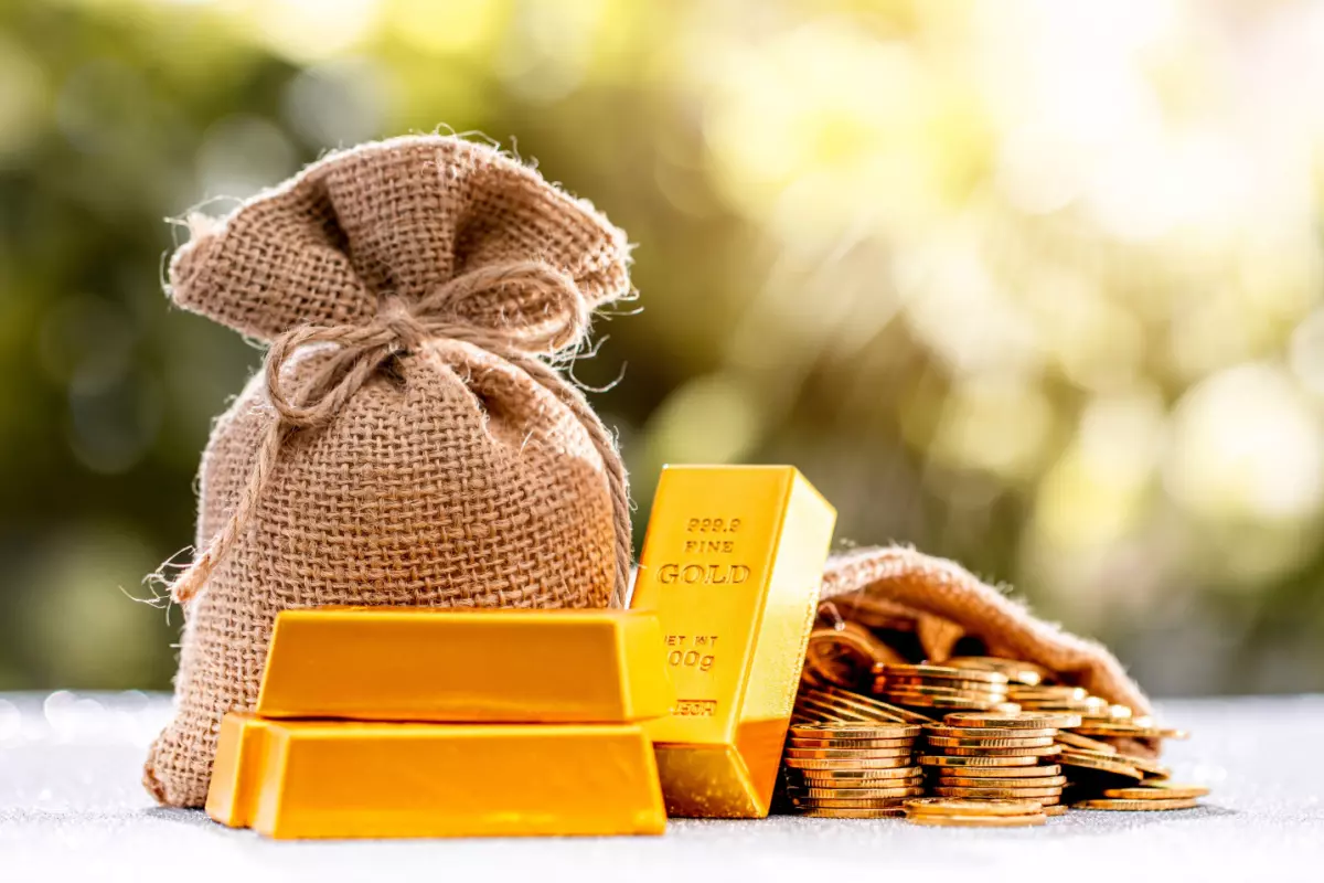 Gold bars and coins next to burlap sack