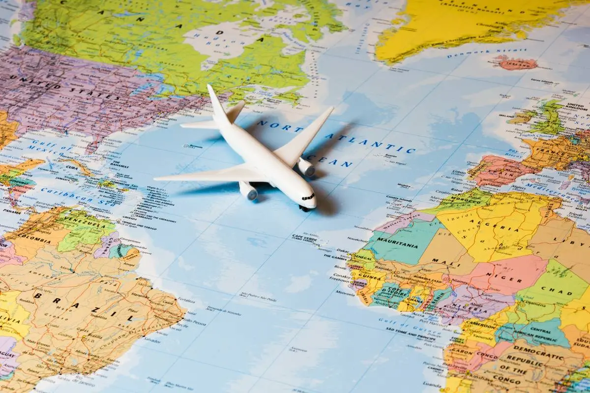 a miniature airplane crossing the Atlantic Ocean on an international world map